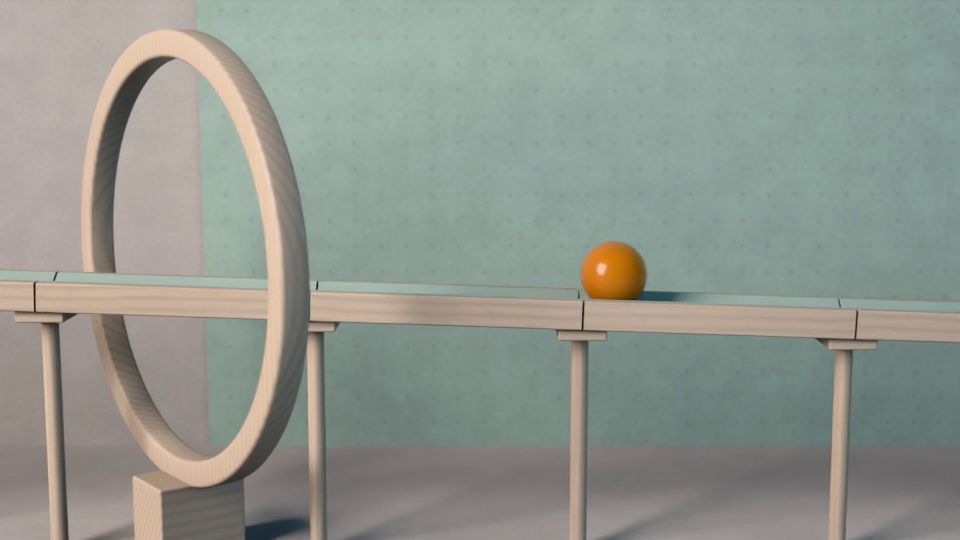 La bola rueda por una rampa larga de haya, junto a un aro de madera, delante de una pared de fieltro verde salvia.